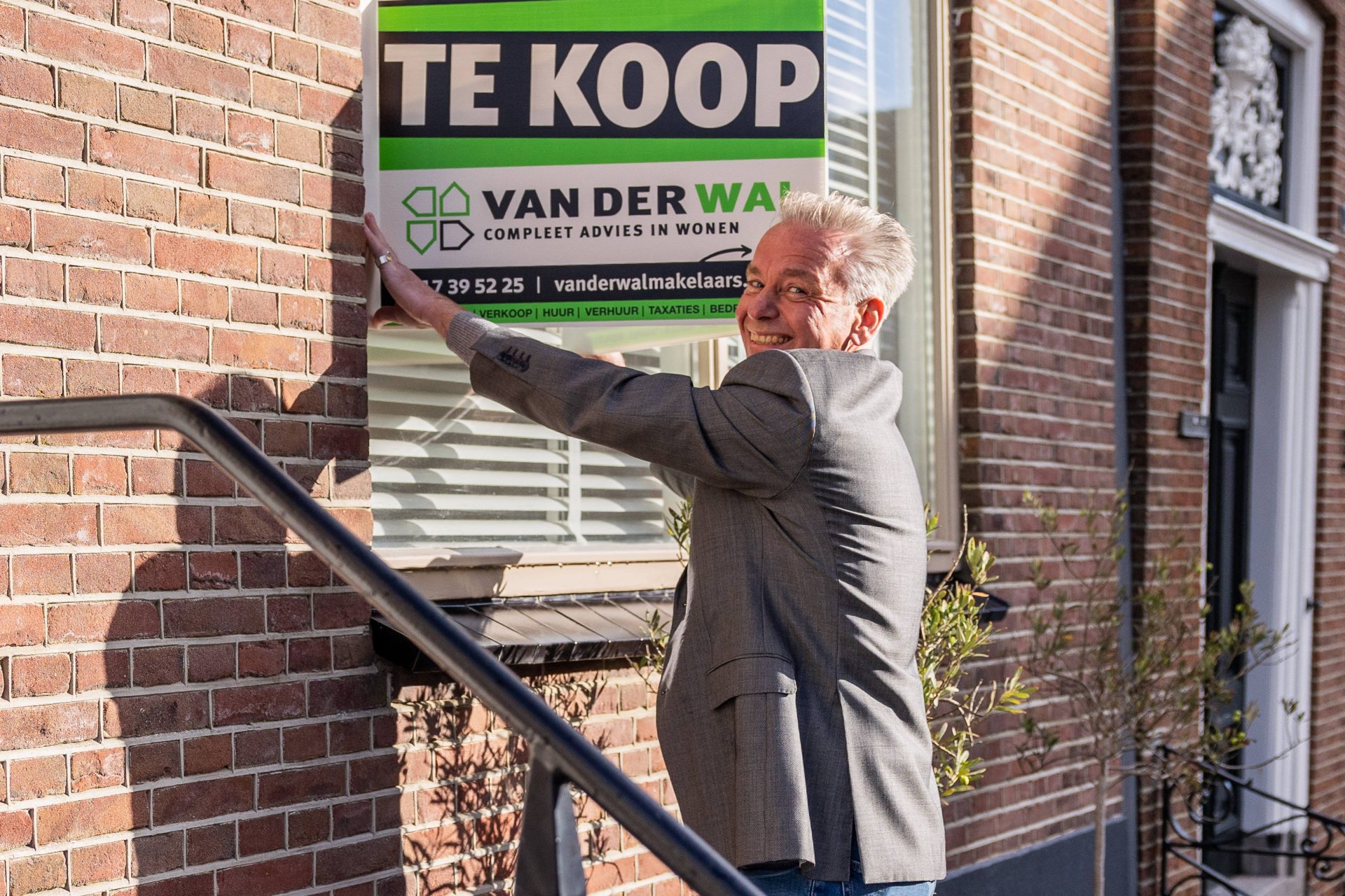 Jeroen Zaagemans plaatst een te koop-bord van Van der Wal Makelaars.